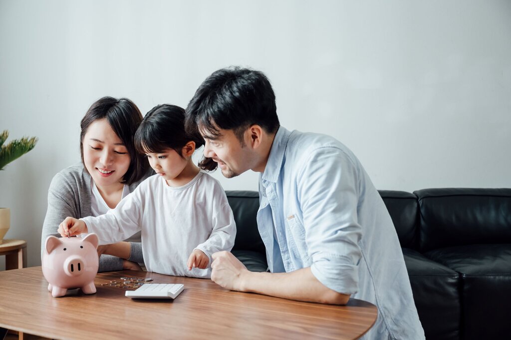 Papa, maman et jeune garçon devant une tirelire